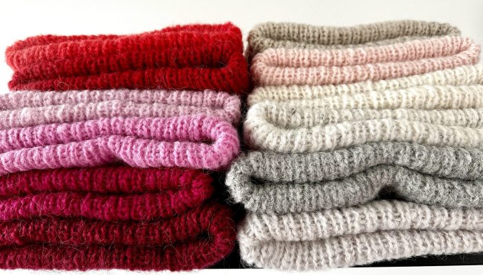 Punaisia ja vaalean sävyisiä pipoja pinossa