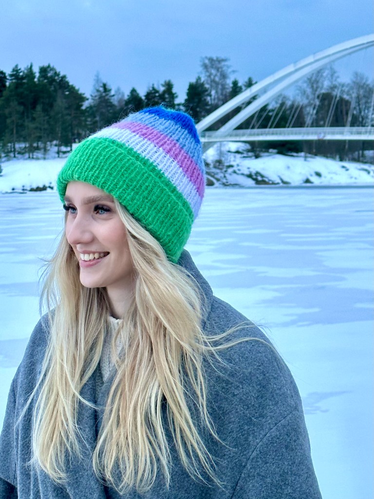 Naisella vihreä ja sinisävyisen raidallinen Colouriche pipo