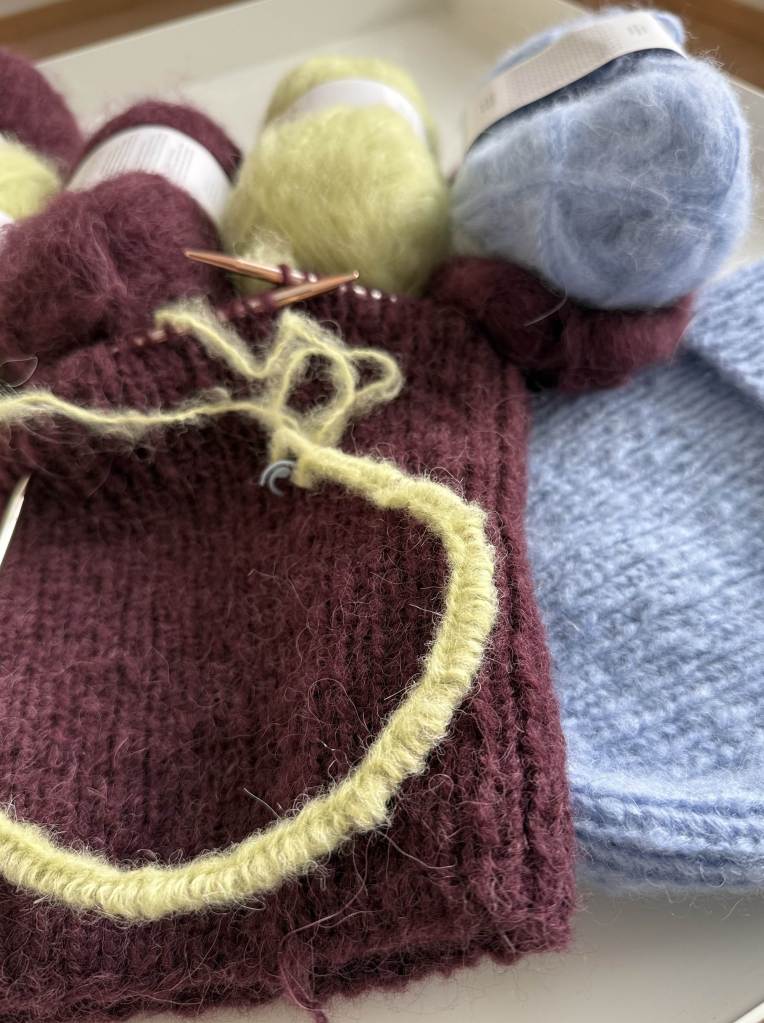 Kuvassa silmukoita pyöröpuikolla ja neulottua joustinneuletta sekä lankoja